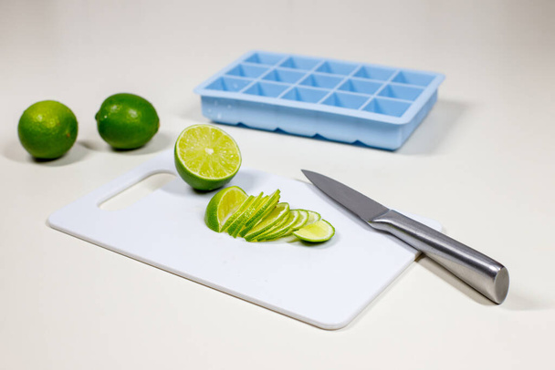 Erfrischende Sommergetränke zubereiten: Eis zubereiten und Limetten schneiden für Limonade und Cocktails - Foto, Bild