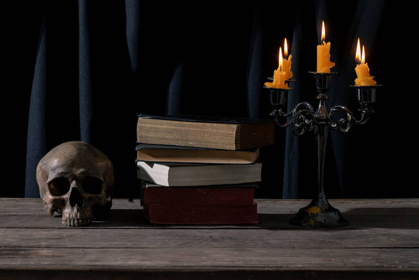 Mytical Candlelit Still Life with Skull and Vintage Books for Halloween and Gothic Themes (en inglés). Naturaleza muerta oscura y atmosférica: cráneo, vela y libros antiguos en un arreglo macabra. - Foto, imagen