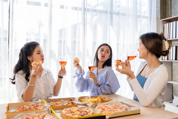 Three Asian girls have a fun pizza party at home at lunchtime. - Foto, Bild