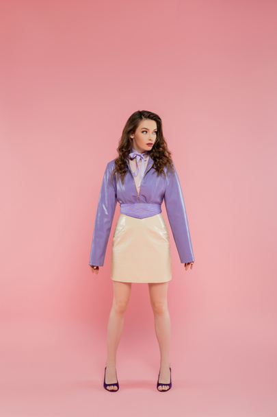glamour, beautiful young woman looking away, fashionable outfit, attractive girl in purple jacket and skirt standing on pink background, studio shot, conceptual, full length of fashionable model  - Фото, изображение