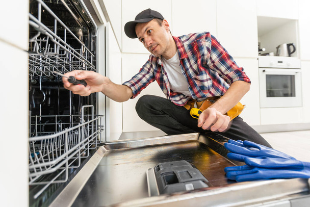 Close-up Of Repairman Fixing Dishwasher With Electric Drill. High quality photo - Fotó, kép