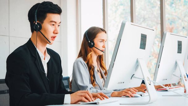 Business people wearing headset working in office to support remote customer or colleague. Call center, telemarketing, customer support agent provide service on telephone video conference call. Jivy - 写真・画像