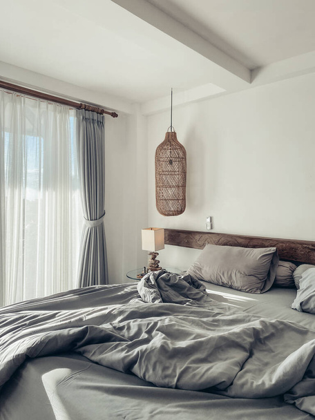 Chambre de style loft avec ensemble de linge de lit gris, lampes suspendues en osier et table de chevet - Photo, image