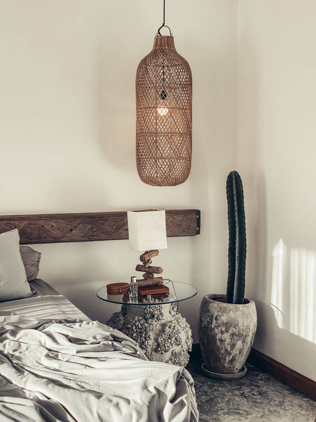 Loft style bedroom with gray bed linen set, hanging wicker lamps and bedside table - Foto, imagen