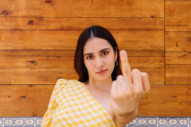 Retrato horizontal de cerca de una mujer hermosa y grosera mostrando el dedo índice a la cámara - Foto, Imagen