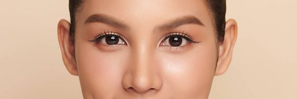 close-up van schoonheid aziatische vrouw oog op beige achtergrond. - Foto, afbeelding