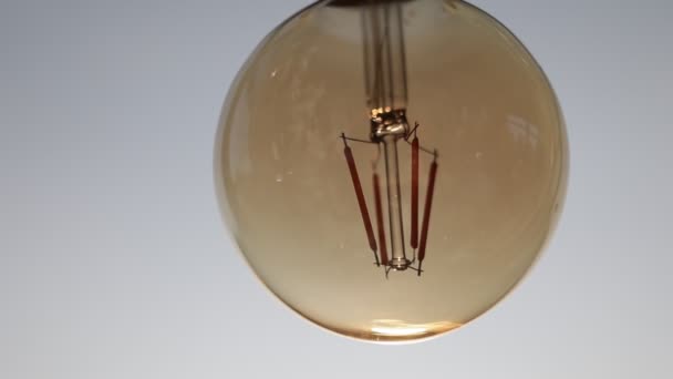 Turned off round electric light bulb with dark glass is hanging on white ceiling. Stylish detail of design interior apartment, restaurant, room. Additional decorative illumination of premises - Footage, Video