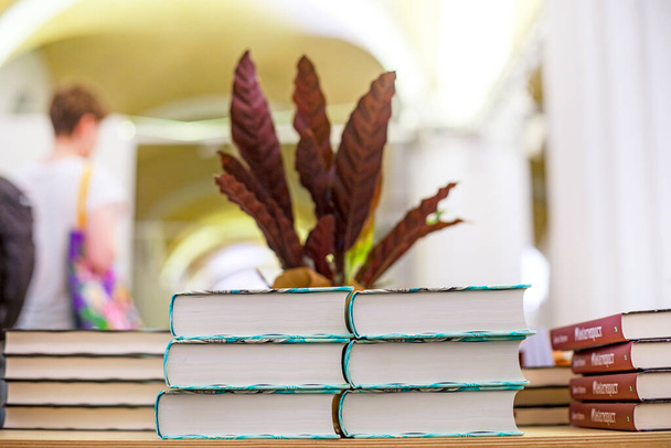 Bücher und Lehrbücher auf einem Holztisch gestapelt auf einem Hintergrund aus Pflanzen im Innenraum. Bildung. Zurück zur Schule - Foto, Bild