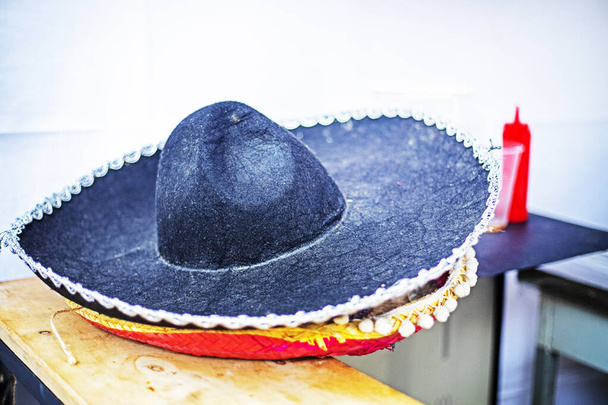 Czarny meksykański kapelusz w szerokim rondzie na ladzie przy piwie i hot dogach. uliczne jedzenie - Zdjęcie, obraz