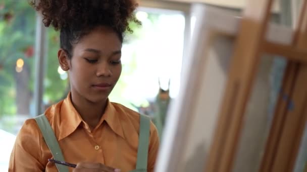 Όμορφη Αμερικανίδα Αφρικανή καλλιτέχνιδα ζωγραφίζει σε στούντιο τέχνης στην τάξη του πανεπιστημίου. - Πλάνα, βίντεο