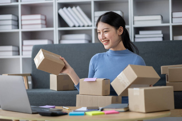 Asian woman online store business owner, online shop owner working from home, posting products for sale on website and accepting orders and packing products for customers with private courier service. - 写真・画像