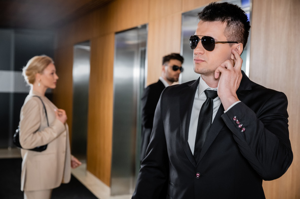 охоронна служба, особистий захист, блондинка в офіційному одязі стоїть поруч з ліфтами, співробітник охорони, що захищає успішну бізнес-леді в готелі, красивий чоловік з вуст  - Фото, зображення