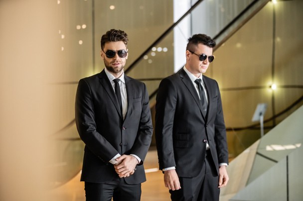security management of luxury hotel, two handsome men in formal wear and sunglasses, bodyguards on duty, safety measures, vigilance, suits and ties, private security, strong guards  - Valokuva, kuva
