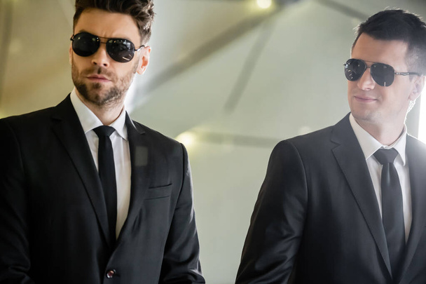 security management, two handsome men in formal wear and sunglasses, bodyguards on duty, safety measures, vigilance, suits and ties, private security, strong guards in luxury hotel - Photo, Image