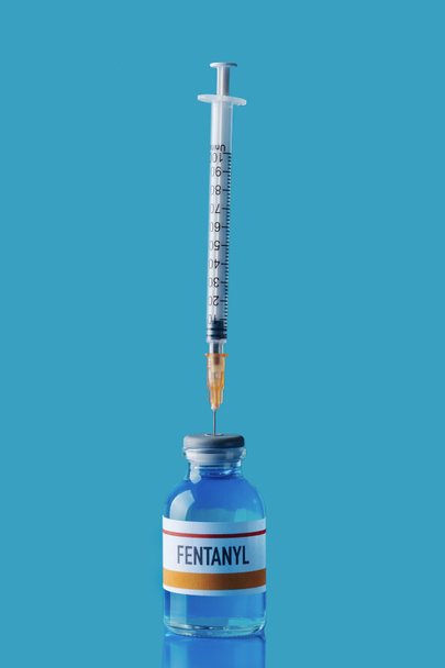 symulowanej fiolki fentanylu ze strzykawką w gumowym korku na niebieskiej powierzchni na niebieskim tle - Zdjęcie, obraz