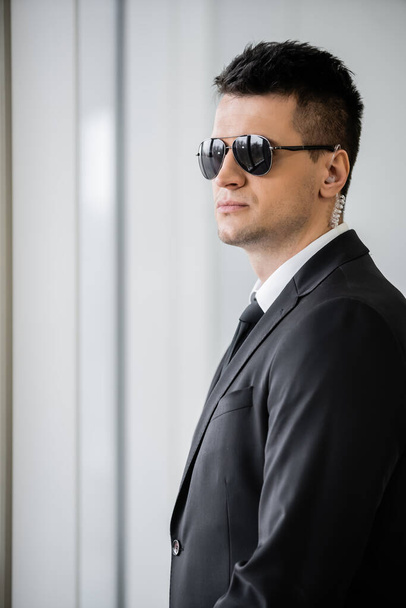 professional headshots, bodyguard with earpiece, good looking man in sunglasses and black suit with tie, hotel safety, security management, surveillance and vigilance, uniformed guard on duty - Photo, Image
