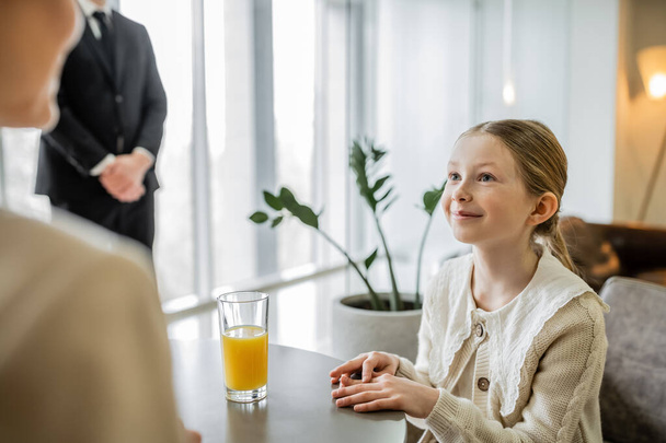 happy preteen girl talking to mother near bodyguard on blurred background, security service, private safety concept, glass of orange juice, personal safety, rich lifestyle,  - Photo, Image