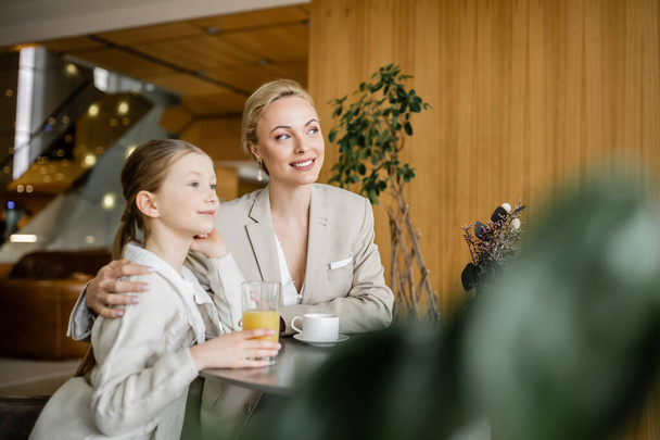 mother and daughter spending quality time together, dreamy blonde woman talking to preteen girl and holding cup of coffee, working parent and kid, modern parenting, family bonding  - 写真・画像