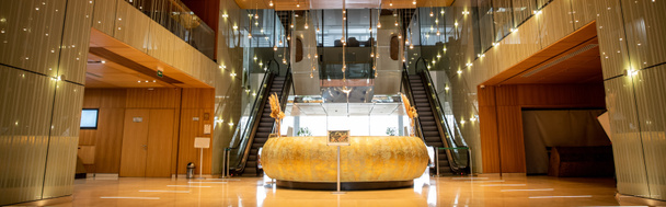 μοντέρνο εσωτερικό του ξενοδοχείου με στρογγυλό γραφείο υποδοχής και εκλεπτυσμένο σχεδιασμό λόμπι, κυλιόμενες σκάλες, κινούμενη σκάλα, πολυτελή ατμόσφαιρα, ευρύχωρα και άνεση, αριστοκρατικό και κομψό, banner  - Φωτογραφία, εικόνα
