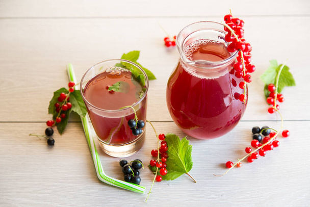 fresh berry juice from red and black currant, on a light wooden table - Foto, Bild