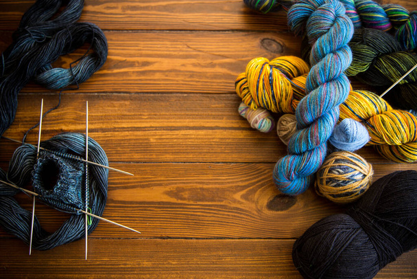 Colored threads, knitting needles and other items for hand knitting, on a dark wooden table . - Foto, afbeelding