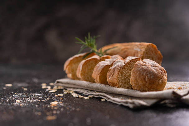 Sliced baguette bread on wooden coaster and rustic background. Artisan Sourdough bread. - Fotó, kép