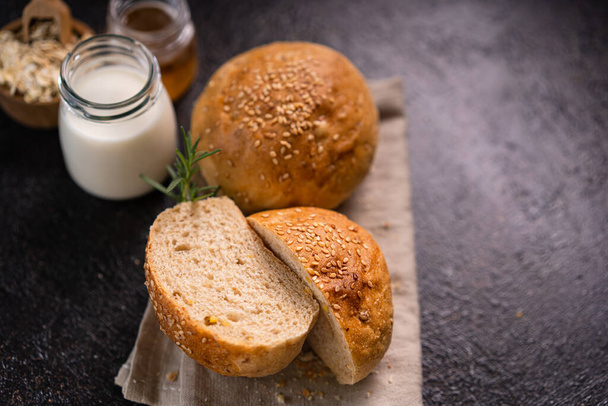 Homemade whole grain brown buns with sesame seeds on rustic background. Healthy artisan bread. - Foto, immagini