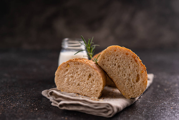 Homemade whole grain brown buns with sesame seeds on rustic background. Healthy artisan bread. - 写真・画像