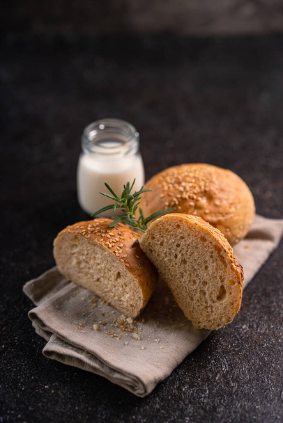 Homemade whole grain brown buns with sesame seeds on rustic background. Healthy artisan bread. - Foto, imagen