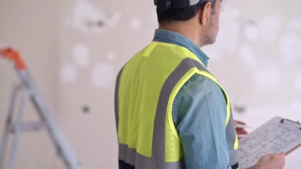 Ammattimaisen arkkitehdin tarkastussuunnitelma ennen korjausprosessin aloittamista asiantuntija liivi seisoo vastaan rakennuslaitteiden valossa lähtökohta - Materiaali, video