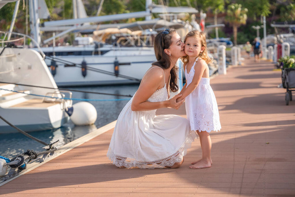 Happy mother and daughter child having fun on luxury yachts on background in marina. Family travel, lifestyle, vacation concept. High quality photo - Foto, Imagem