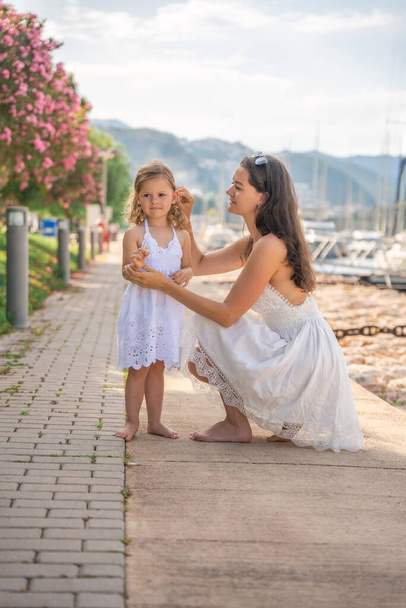 Szczęśliwa matka i córka dziecko bawiące się na luksusowych jachtach na tle w marinie. Podróże rodzinne, styl życia, pomysł na wakacje. Wysokiej jakości zdjęcie - Zdjęcie, obraz