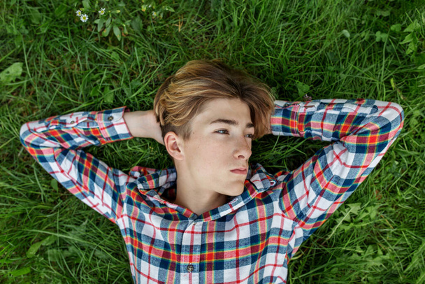 Портрет серьезного подростка, который лежит в траве и отдыхает. Генерал А. Развитие идентичности. - Фото, изображение
