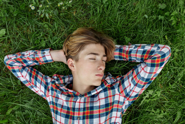 Portrait of serious teenager who lies in grass and rests. Gen Z. Identity development. Sleep. - Fotografie, Obrázek