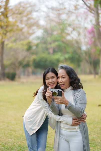 Anıları yakalamak için parkta kamerayla yürüyen Asyalı genç anne ve kız.. - Fotoğraf, Görsel