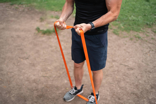 Middle age man doing strength exercises with resistance bands outdoors in park . High quality photo - Foto, Bild