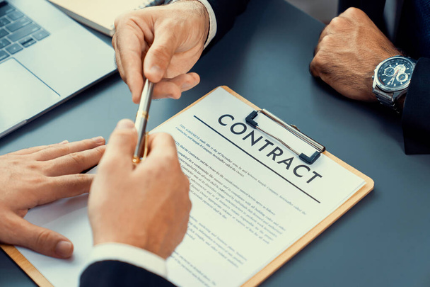 Two businesspeople sit across the desk as business deal is taking place. Corporate attorney giving a pen for client or partner to sign contract paper, sealing the deal with signature. Fervent - Photo, Image