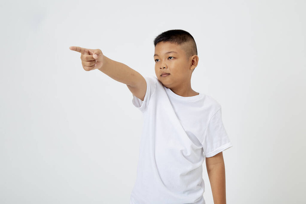 Beyaz tişörtlü yakışıklı Asyalı çocuk izole edilmiş bir stüdyoda beyaz arka planda kameraya bakıyor. - Fotoğraf, Görsel