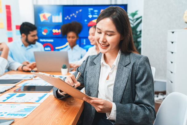 Portrait of happy young asian businesswoman with group of office worker on meeting with screen display business dashboard in background. Confident office lady at team meeting. Concord - Фото, изображение