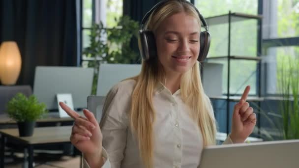 Kaukázusi nő lány tart munkaszünetet az irodában nyugodt üzletasszony mosoly hallgatni zenét fülhallgató laptop online zenei szolgáltatás üzleti menedzser hallgat fülhallgató élvezze dallam tánc lépés - Felvétel, videó