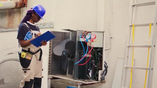 Professional wireman commissioned for external air conditioner routine check up, writing findings on clipboard. Specialist doing hvac system investigation of damaged parts - Footage, Video