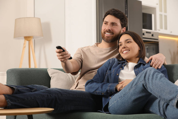 Happy couple watching TV on sofa at home - Foto, immagini