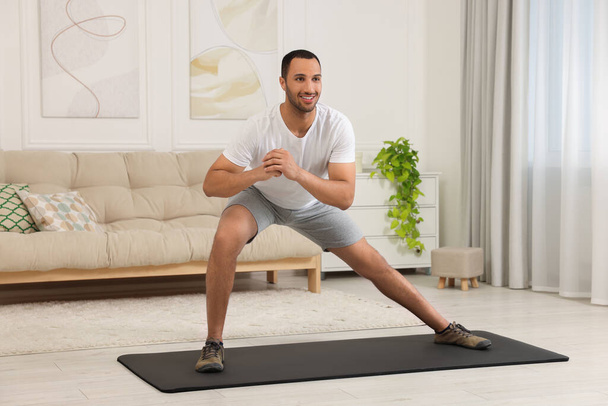 Man doing morning exercise on fitness mat at home - Foto, afbeelding