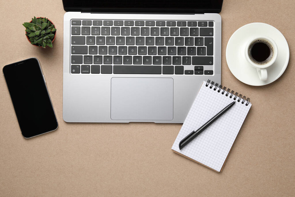 Modern laptop, notebook and cup of coffee on beige table, flat lay. Space for text - Fotó, kép