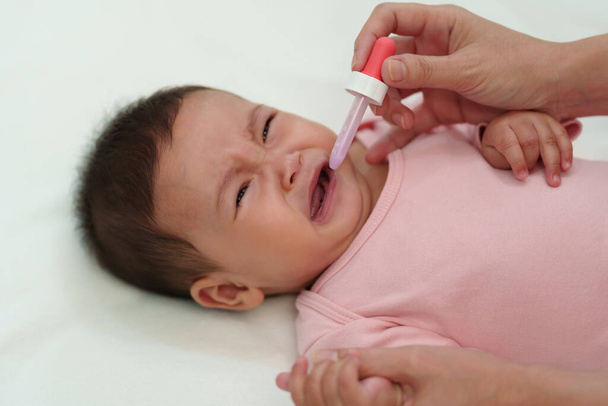 sick infant baby crying while refuses eating liquid medicine with a dropper - Photo, image