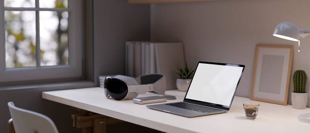 Close-up image of a laptop computer white screen mockup, modern VR goggles, coffee cup, and accessories on a table. Modern home workspace. 3d render, 3d illustration - Фото, зображення