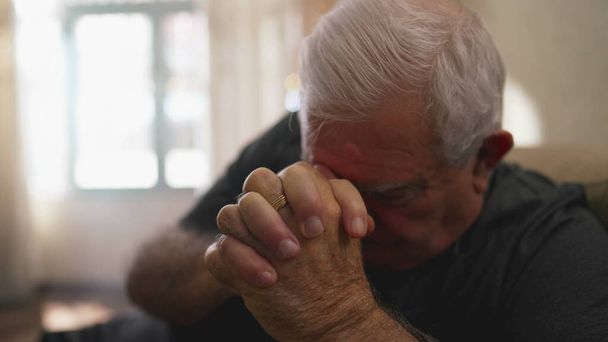 Reményteli öregember, aki otthon imádkozik magányosan. Hűséges idősebb kaukázusi férfi, szorított kézzel, FAITH-tal - Fotó, kép