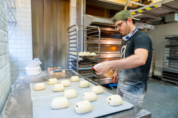 Baker of bakery in workshop workshop of artisan bakery preparing croissant and neapolitan - Foto, imagen