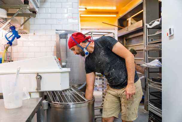 Male baker of bakery in the workshop of artisan bakery preparing the sourdoughs in the machines - Φωτογραφία, εικόνα