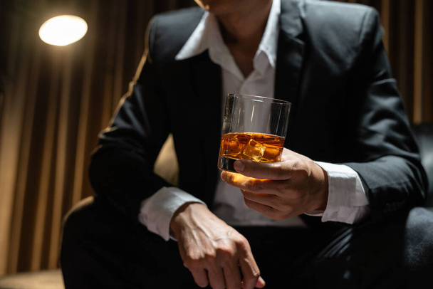 Бизнесмен, сидящий с бокалом виски в винном магазине - Фото, изображение